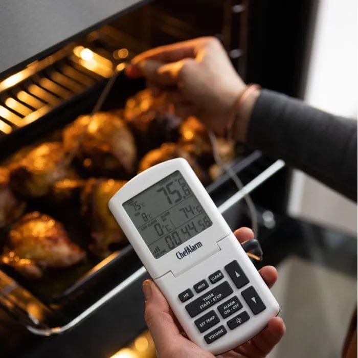 une personne tenant un Thermometre.fr Thermomètre et minuterie ChefAlarm dans un four.
