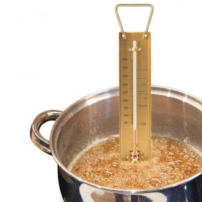 Un thermomètre Thermometre.fr à sucre et à confiture en laiton est placé dans une casserole de sucre bouillante.